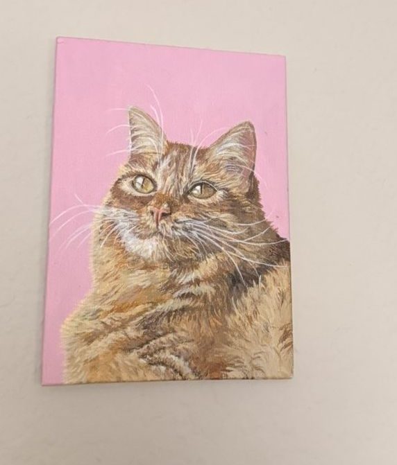 Cheez-It, a ginger cat painted against pink, hanging on the owner's wall