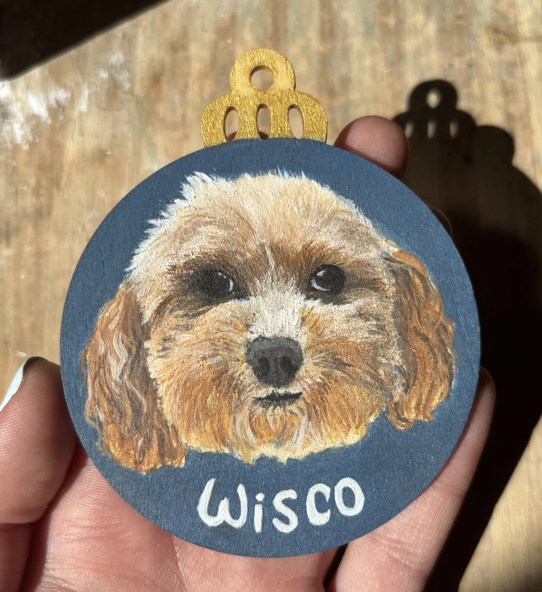 Wisco, a fluffy dog hand-painted on a round wooden Christmas ornament