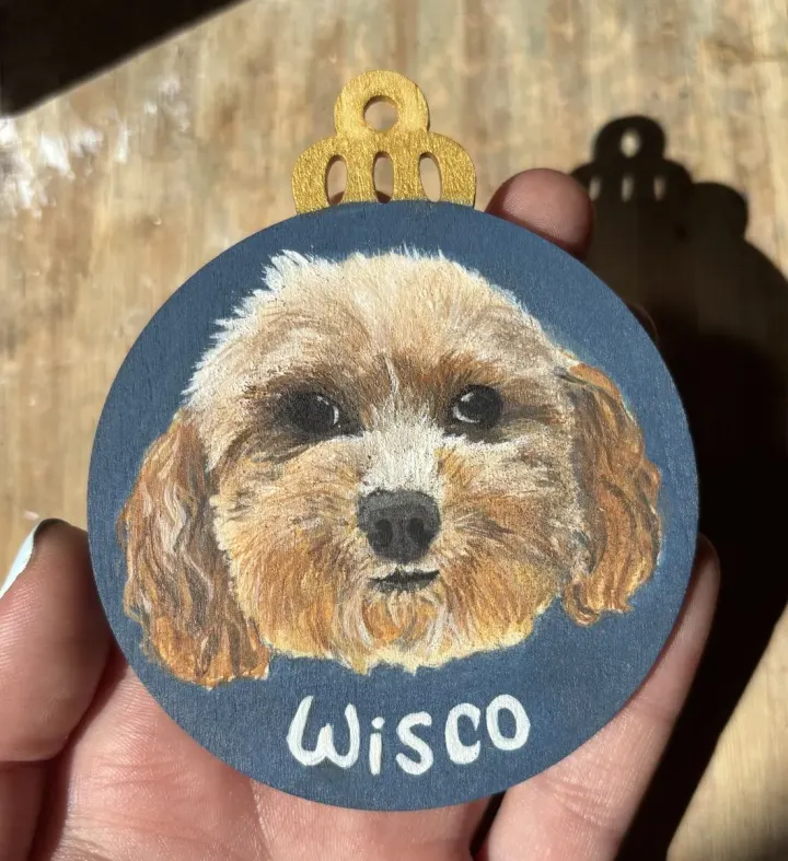 Wisco, a fluffy dog hand-painted on a round wooden Christmas ornament